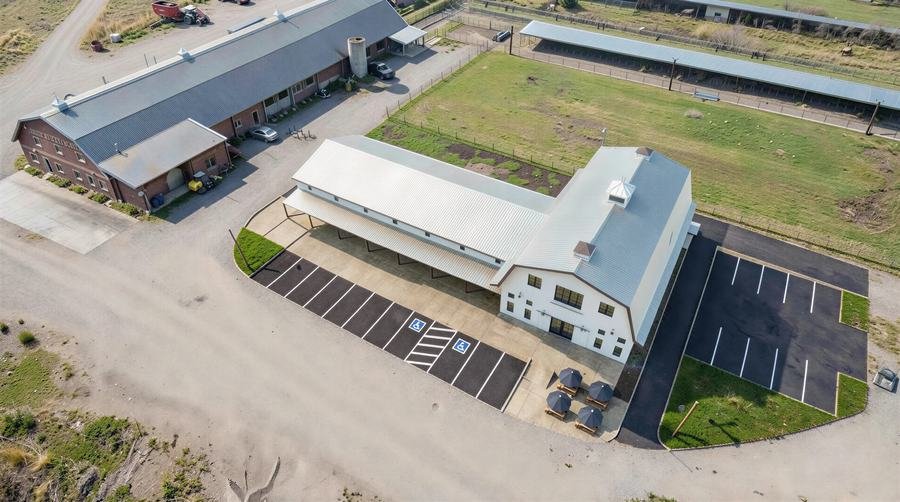 Aerial rendering of a proposed creamery building's site plan, showing parking, covered porch, and its position relative to the existing farm buildings.
